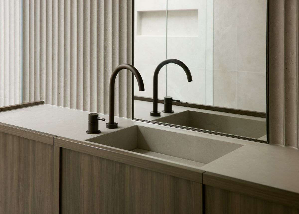 Two matt black Par Taps basin mixers over a concrete basin, with a fluted wall and mirror